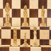 A chess set with pieces featuring ancient Egyptian motifs and figures, placed on a chess board.
This beautiful chess set depicts figures from the civilisation of Ancient Egypt, a society which began around
3150BC, growing rapidly along the  banks of the River Nile. Trade with other countries and its agricultural security helped it to become enormously prosperous; and due to this great wealth the rulers, known as Pharaohs, were very powerful, as were its priests.